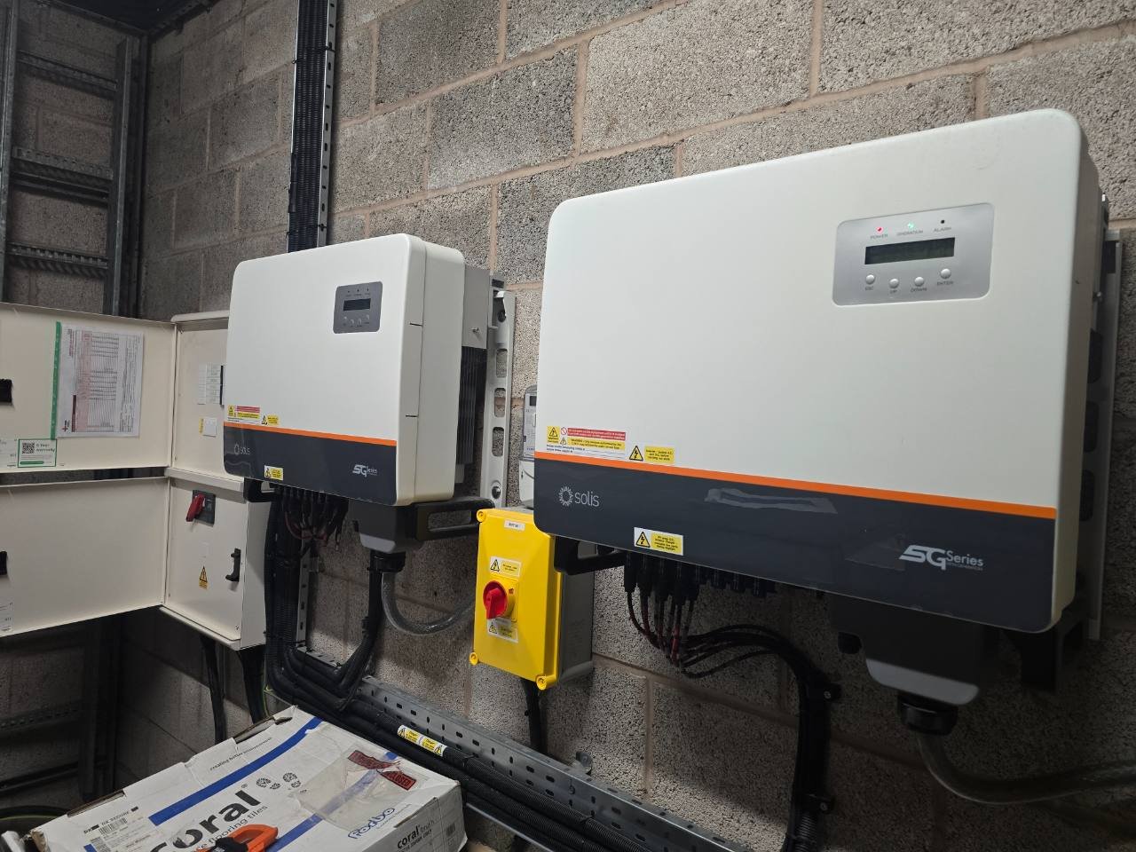 Twin Solis solar inverters on a wall with yellow isolators and neat cable tray