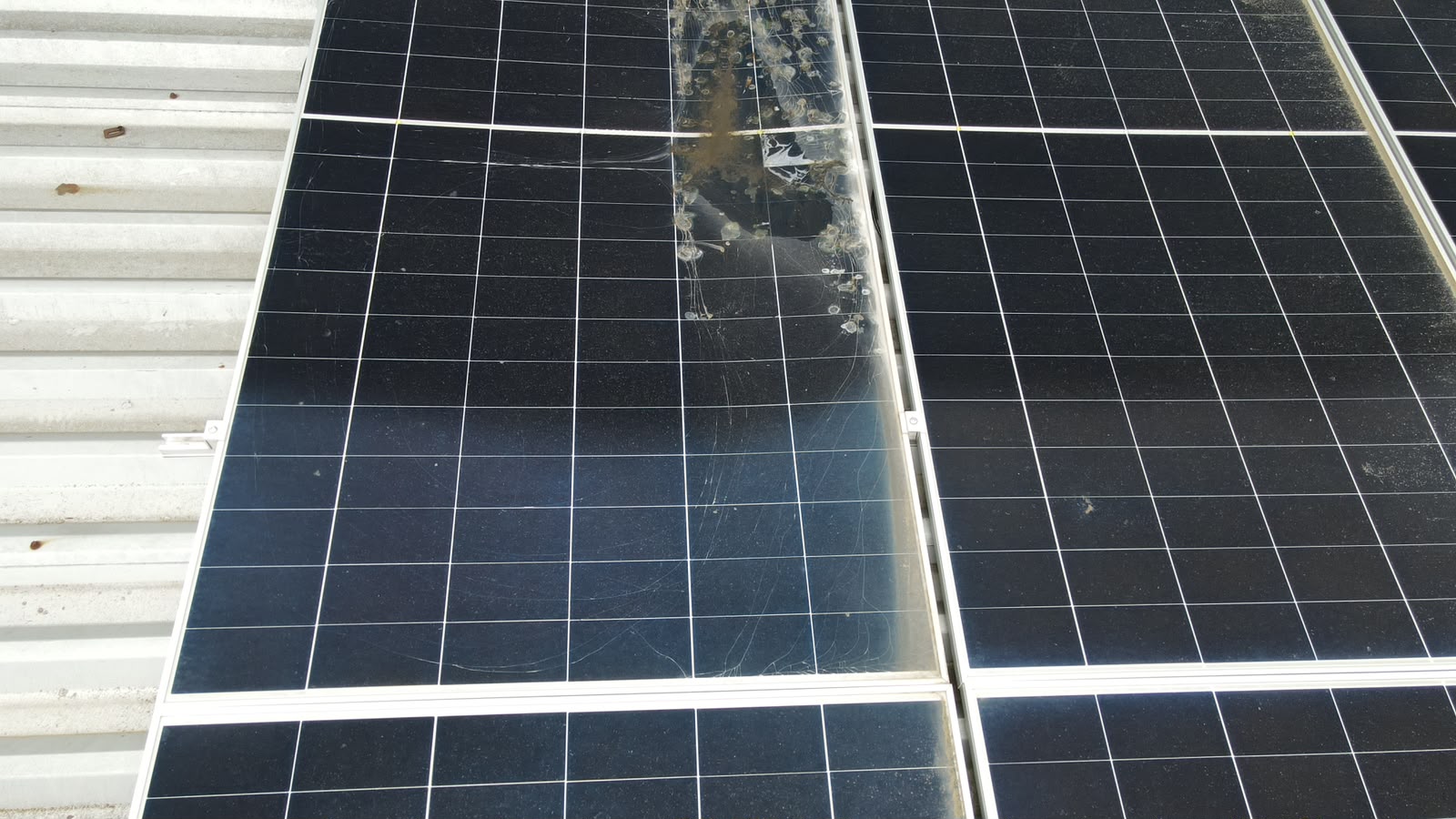Cracked solar module glass with impact damage on a metal roof array
