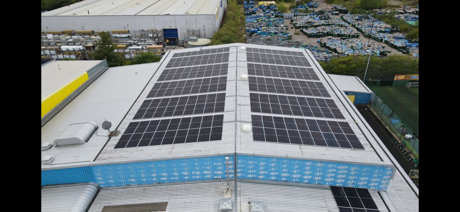 Overhead drone view of commercial solar arrays on an industrial metal roof